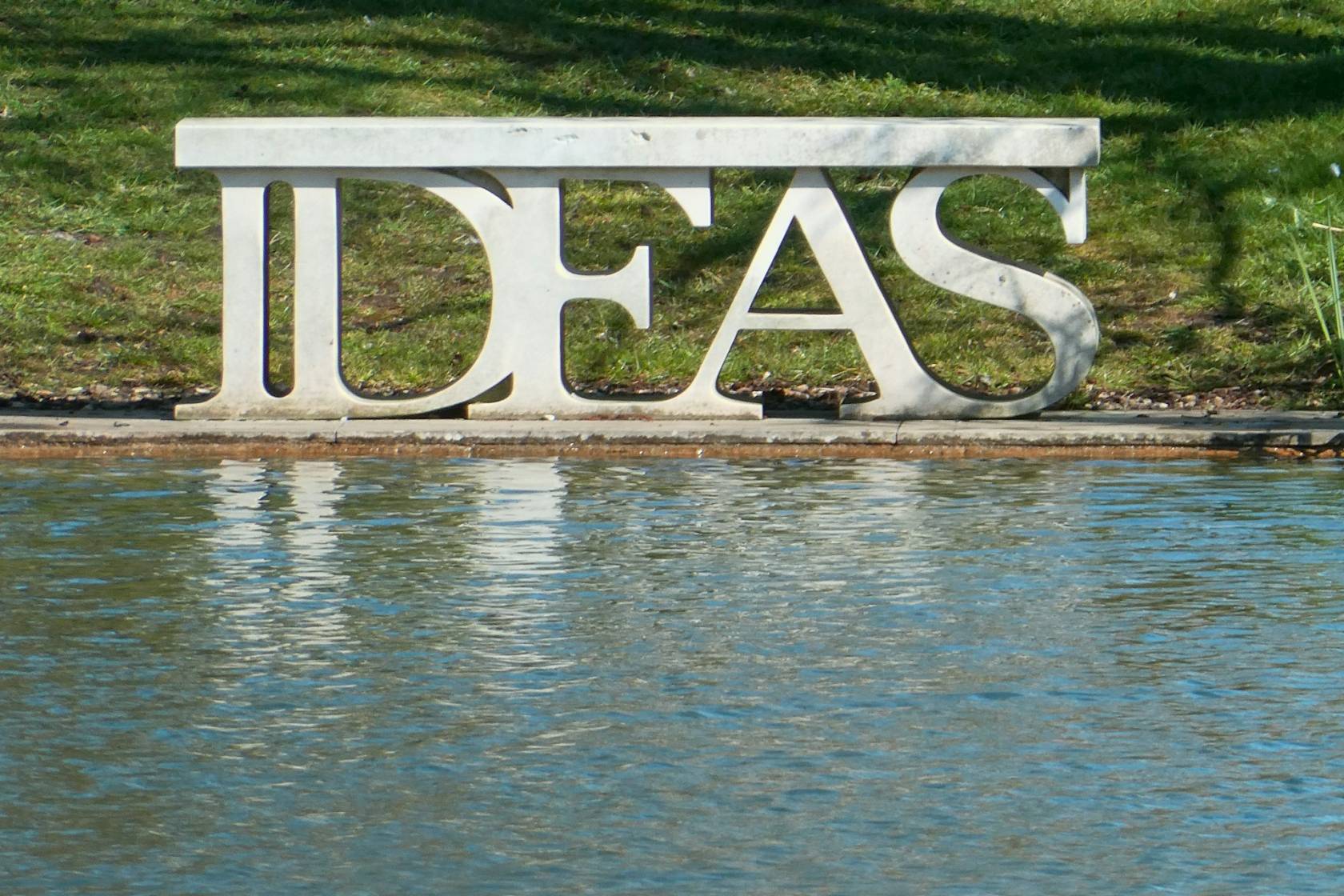 "Image of a serene park with a fountain and lush green lawn, with text overlay saying 'IDEAS'."